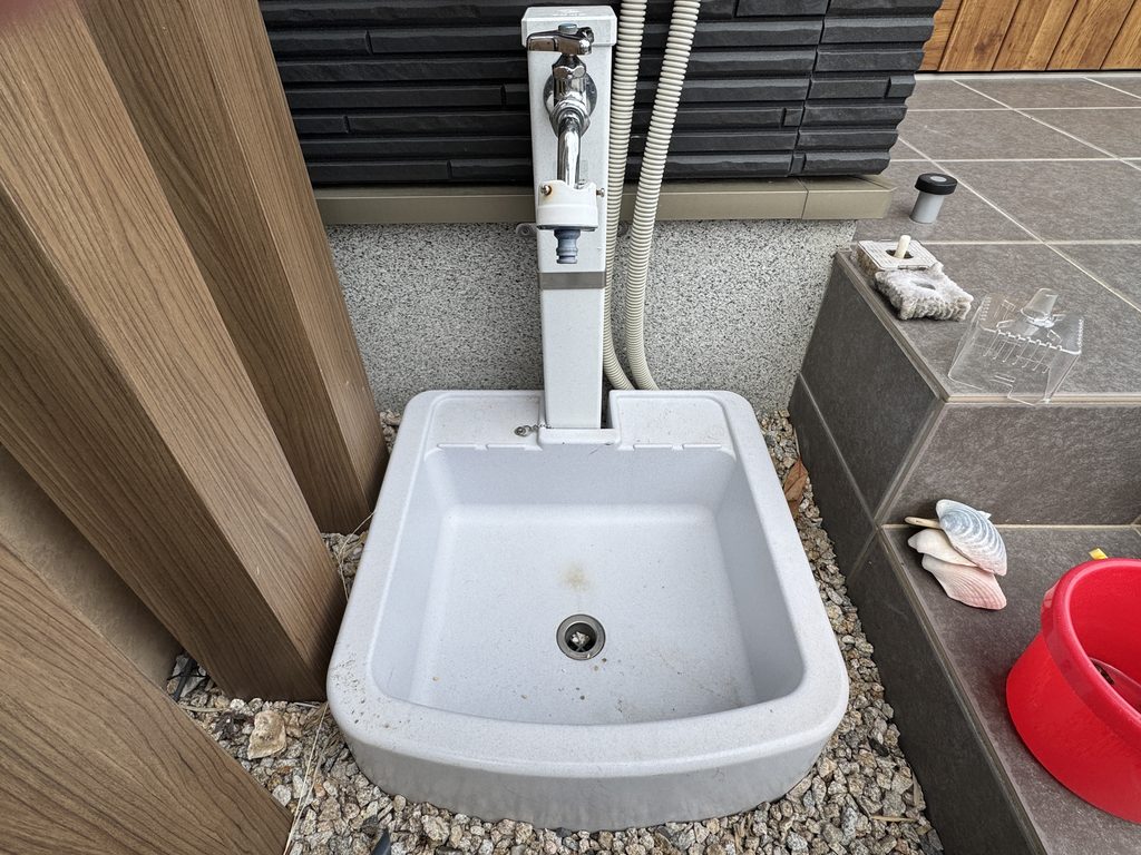 標準仕様の屋外水栓と水受け。水受けは小さく、周りは砂利になっている